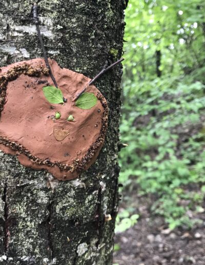 Un visage d'argile sur un tronc d'arbre